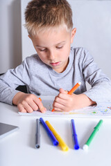 small caucasian left handed blond kid drawing with felt pens on the living room