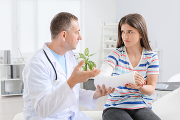 Young woman with broken arm visiting doctor in clinic