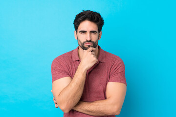 Young handsome man with beard over isolated blue background thinking