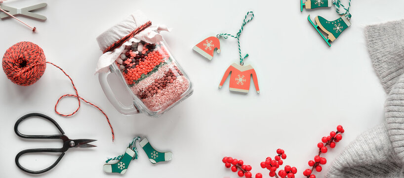 Zero waste Christmas panoramic image. Gift in a jar, layered bean mixture with spices on white background with wooden winter Xmas decorations.