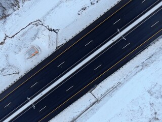Aerial view black canvas of a new high-speed highway with applied road markings against the background of white snow