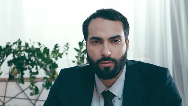 bearded hispanic businessman looking at camera in office