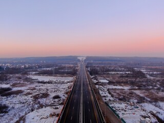 Aerial view of the Central Ring Road (CKAD) at sunrise. Beautiful panoramic landscape of a straight road overlooking the horizon. Travel by car in winter