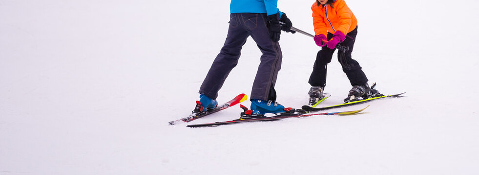 Professional ski instructor is teaching a child to ski on a day on a mountain slope resort with snow. Family and children active vacation.