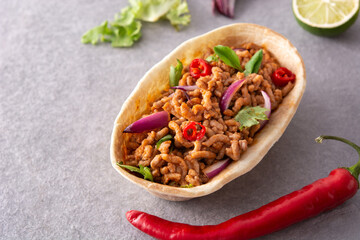 Mexican barquita taco with beef, chilli, tomato, onion and spices on gray stone