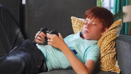 Alone young kid playing video game using joystick during late night while sleeping on bed - concept of kids game addiction and late night playing games - Powered by Adobe
