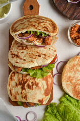 Lavash salad with fried chicken and vegetables. Pita with chicken nuggets, tomatoes, red onions and lettuce and sauce. Healthy fast food. Top view. White background.