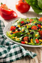 Mexican salad with black beans, corn,tomatoes,lettuce and pepper on wooden table	