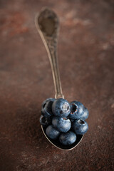 Blueberries on vintage spoon on concrete surface.