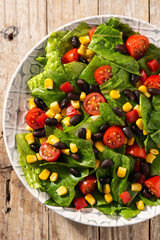 Mexican salad with black beans, corn,tomatoes,lettuce and pepper on wooden table	