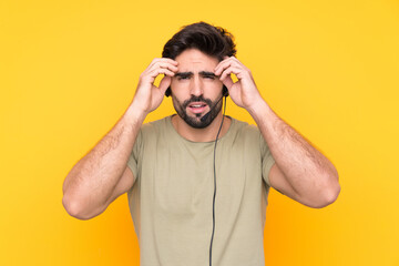 Telemarketer man working with a headset over isolated yellow background unhappy and frustrated with something. Negative facial expression