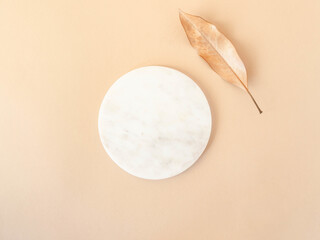 Marble white podium with a natural leaf on beige background