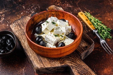 Salad with fresh feta cheese, thyme and olives. Dark background. Top view