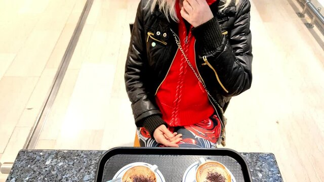 young girl removing the surgical mask before drinking breakfast coffee in Italian cafe shop. Italian containment precautions by social distancing for Coronavirus COVID-19 pandemic in Italy.