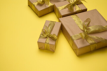 box wrapped in brown paper and tied with a golden ribbon with a bow, gift on a yellow background