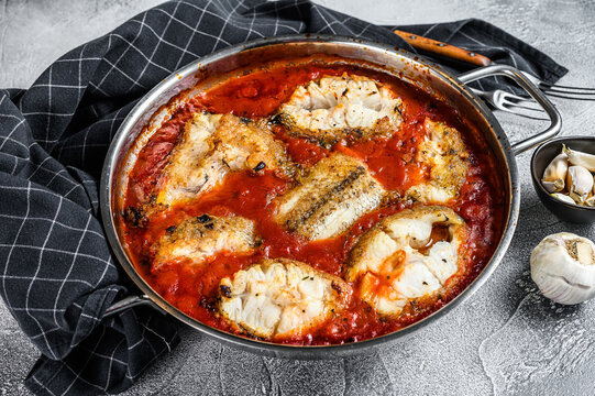 Baked Grenadier Macrurus White Fish With Tomato In A Pan. White Wooden Background. Top View