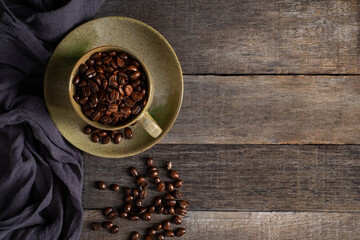 Top view above of Black coffee seed for morning menu in brown ceramic cup with coffee beans roasted on old wooden table background. Flat lay with copy space.