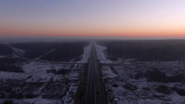 Aerial view of the Central Ring Road (CKAD) at sunrise. Beautiful panoramic landscape of a straight road overlooking the horizon. Travel by car in winter