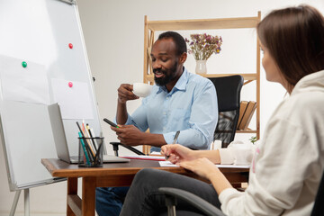 Lesson. English courses at home. Smiling african man teaches student, explaining in interior of...