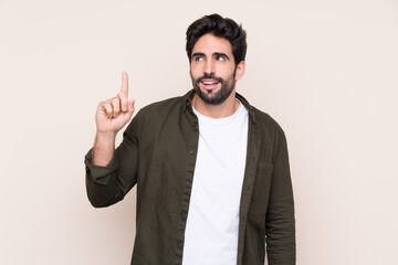 Naklejka premium Young handsome man with beard over isolated background intending to realizes the solution while lifting a finger up