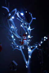 Christmas decorations hanging from a minimal white tree with lights