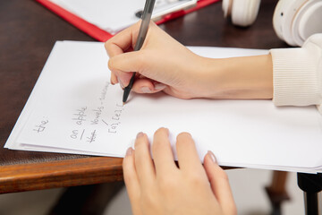 English courses at home. Close up hands of teacher and student during lesson in interior of living room. Using devices, writing, explaining. Concept of remote education, quarantine, modern gadgets.