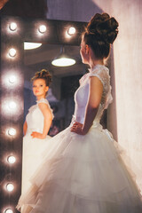 Fototapeta premium Beautiful young bride with wedding makeup and hairstyle. Reflection of the bride in the mirror.
