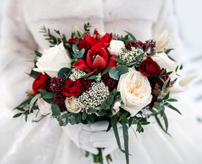 Wedding bouquet of red and white roses in the hands of the bride