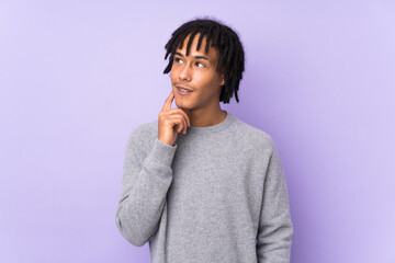 Young african american man isolated on purple background thinking an idea while looking up