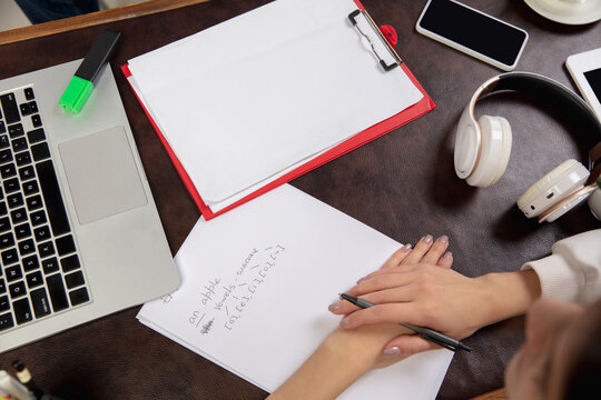 English courses at home. Close up hands of teacher and student during lesson in interior of living room. Using devices, writing, explaining. Concept of remote education, quarantine, modern gadgets.