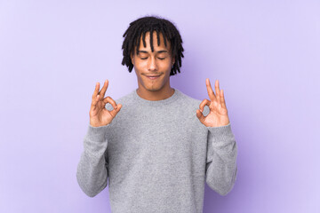 Young african american man isolated on purple background in zen pose