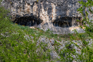Karst caves front view, having the shape of two huge black eyes near main entrance of Prohodna...
