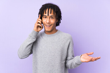 Young african american man isolated on purple background keeping a conversation with the mobile phone with someone