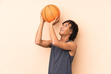 Young african american man isolated on beige background playing basketball