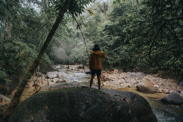 Male traveler explore the beautiful of rainforest stream in the morning.Male traveler camping in the rainforest.Grain effects and tone color applied.