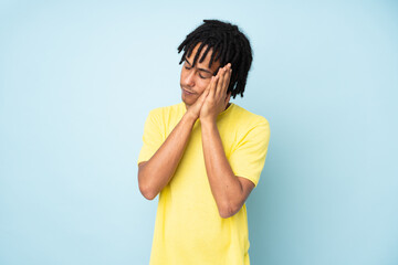 Young african american man isolated on blue background making sleep gesture in dorable expression