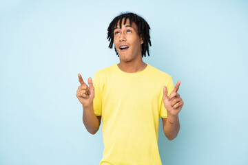 Young african american man isolated on blue background surprised and pointing up