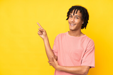 Young african american man isolated on yellow background pointing finger to the side