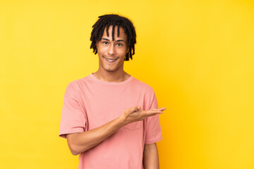 Young african american man isolated on yellow background presenting an idea while looking smiling...
