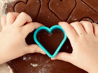 A child's hand makes heart-shaped cookies. Valentine's day. Christmas