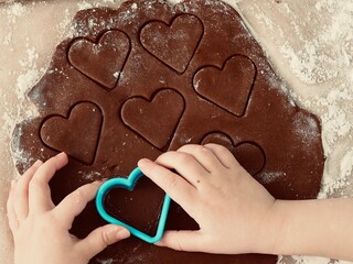 A child's hand makes heart-shaped cookies. Valentine's day. Christmas