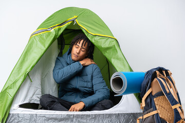 Young african american man inside a camping green tent suffering from pain in shoulder for having...