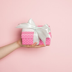 Colorful pink polka dot gift in female, minimal background composition card