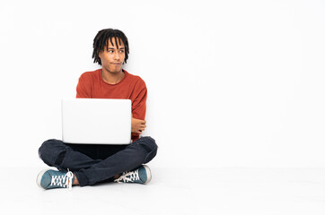 Young african american man sitting on the floor and working with his laptop portrait