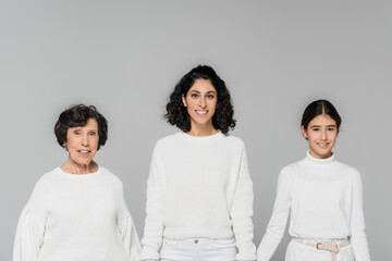 Three generations of hispanic women smiling at camera isolated on grey