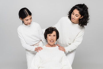 Hispanic woman and child hugging senior granny isolated on grey, three generations of women