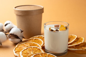 gift box, milk candle in a glass, twigs and citrus fruits, close-up, pastel colors.