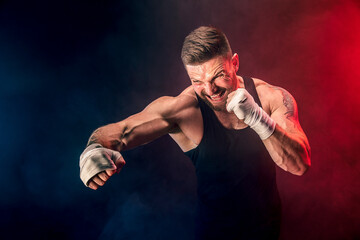 Sportsman muay thai boxer fighting on black background with smoke. Sport concept.
