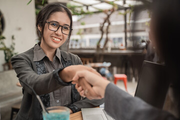 Young business woman meeting shake hands in a cafe