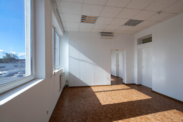 Modern interior of empty office rooms. White walls and door. Huge windows. Sunny day. Air conditioner.